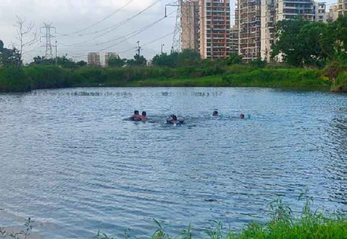 Adults and children using tyres to swim at Taloja Jail pond